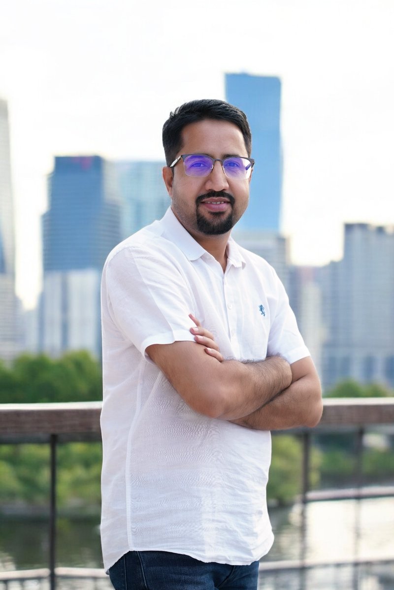 Dhanpat Saran, Founder and CEO of Axis Web Art, standing with arms crossed against a city skyline